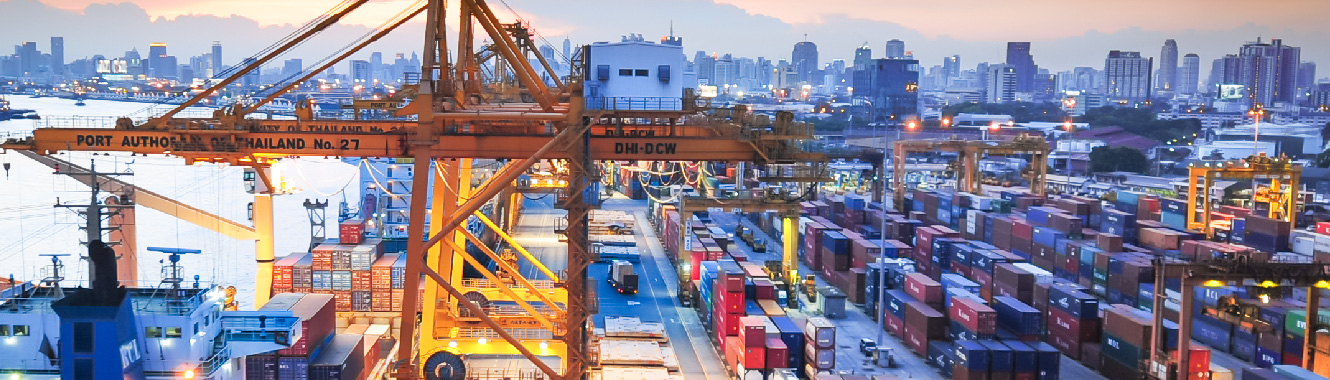 A shipping yard full of storage containers and heavy machinery such as cranes and trucks.