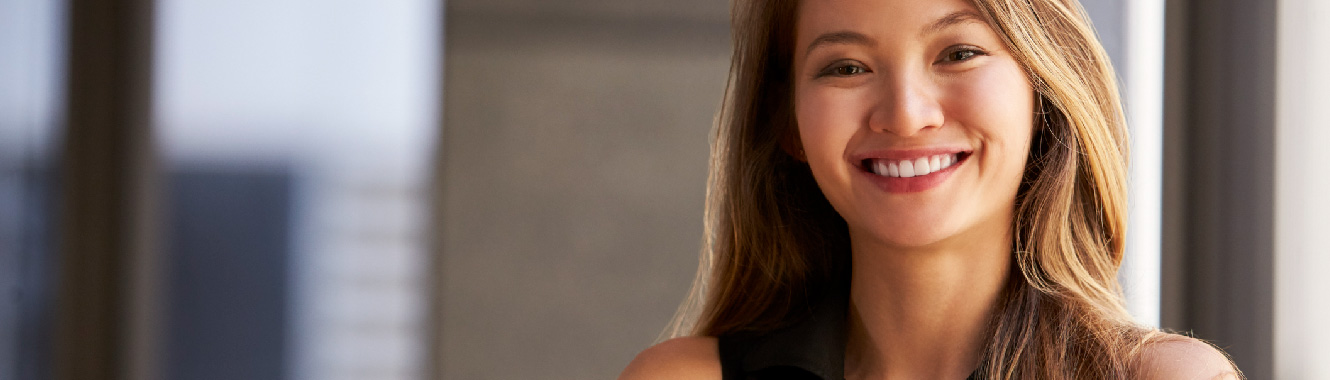 A young confident businesswoman has her arms folded and is smiling at the camera.