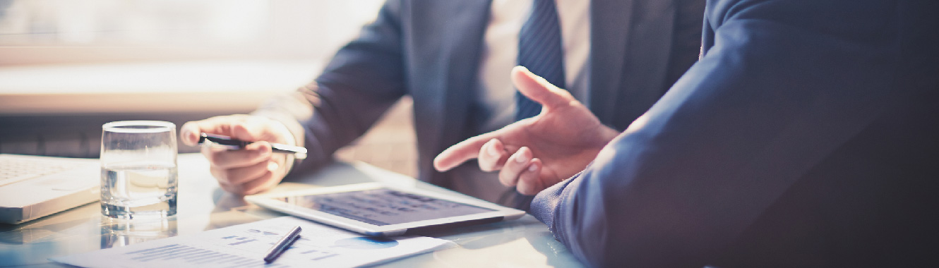 Two business people having a meeting, one of them is pointing at a tablet screen.